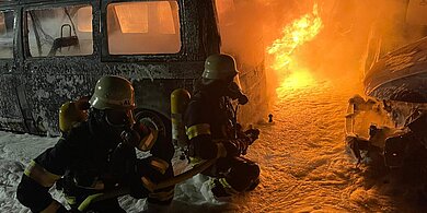 Feuerwehr löscht bei Dunkelheit brennende Fahrzeuge mit Schwerschaum 